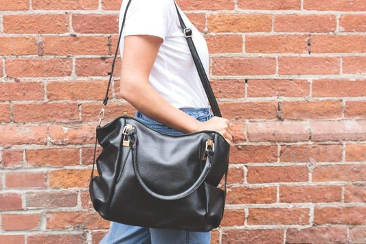 a person with a backpack and suitcase on a brick wall 